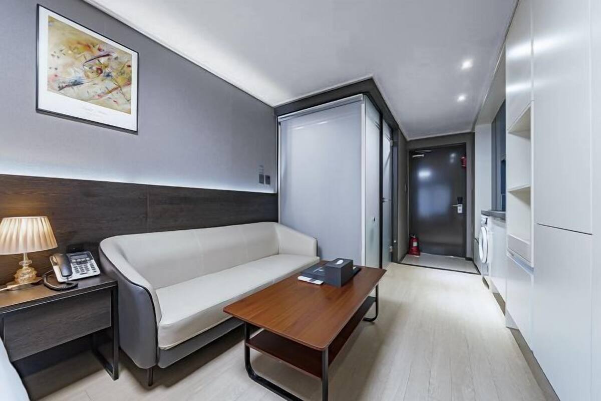 Habitació d'hotel moderna amb un sofà, una taula de fusta, una làmpada, un telèfon i un quadre a la paret.