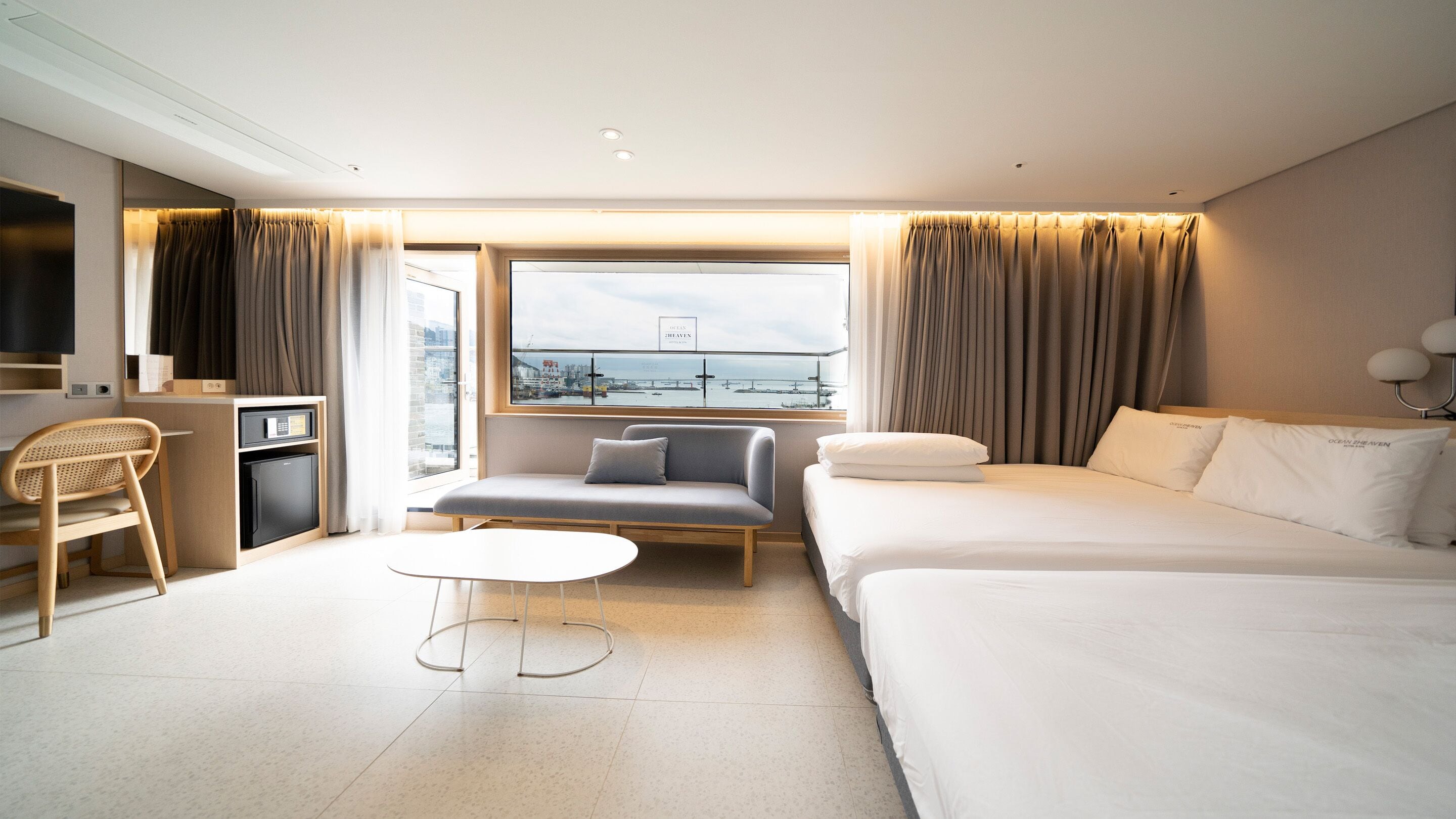 Habitación de hotel con cama, sofá, escritorio, silla y ventana con vista a la ciudad.