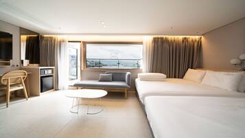 Habitación de hotel con cama, sofá, escritorio, silla y ventana con vista a la ciudad.
