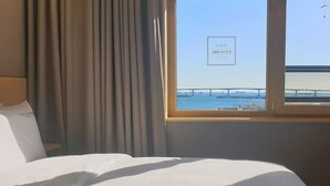 A hotel room with a bed, a window with a view of a bridge and the sea, and a sign reading "Ocean 2Heaven Hotel & Spa". - Nampo Ocean 2 Heaven Hotel&Spa (Busan)