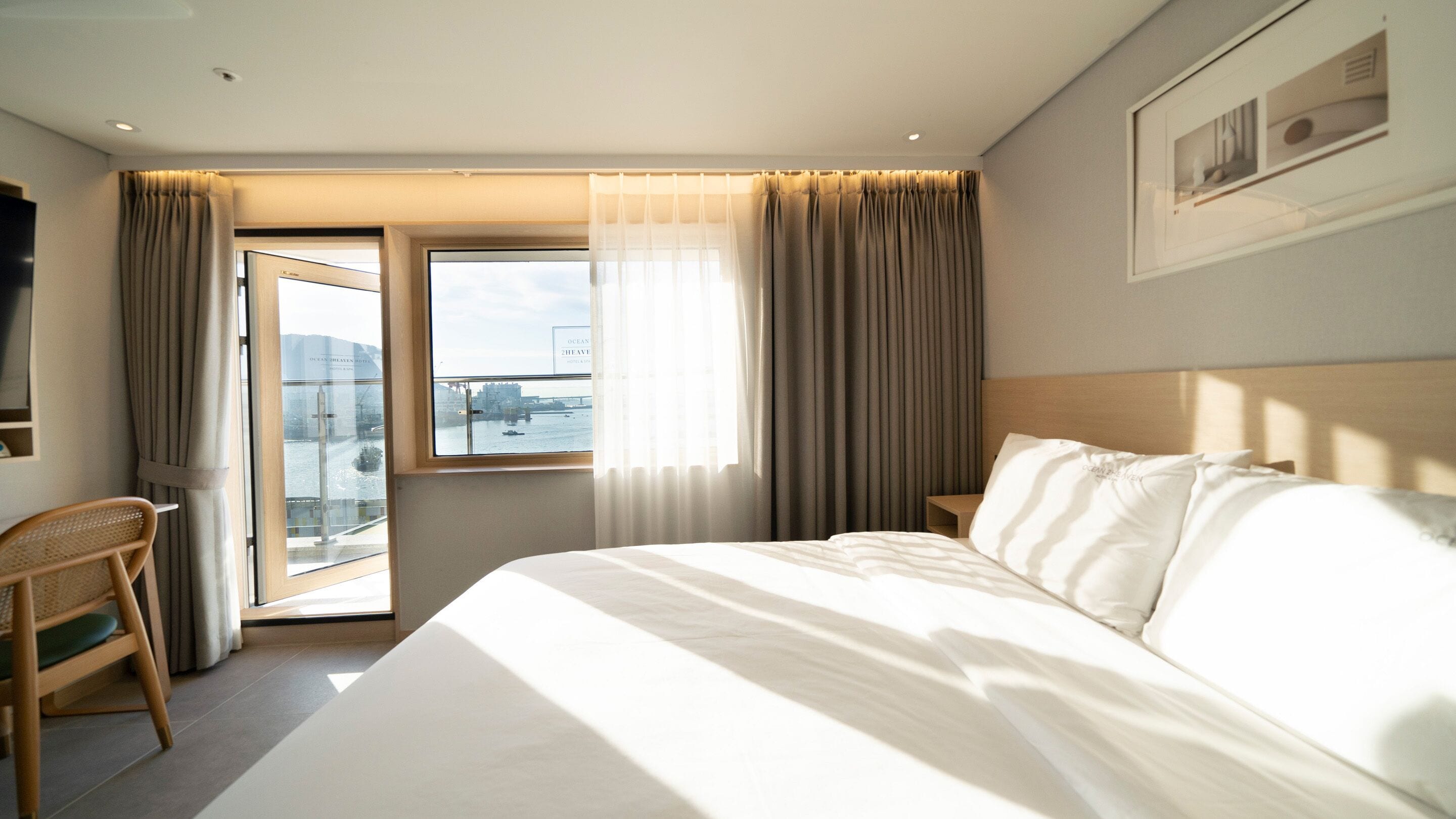 Una camera d'albergo con un letto grande, una sedia, una scrivania e una finestra con tende.
