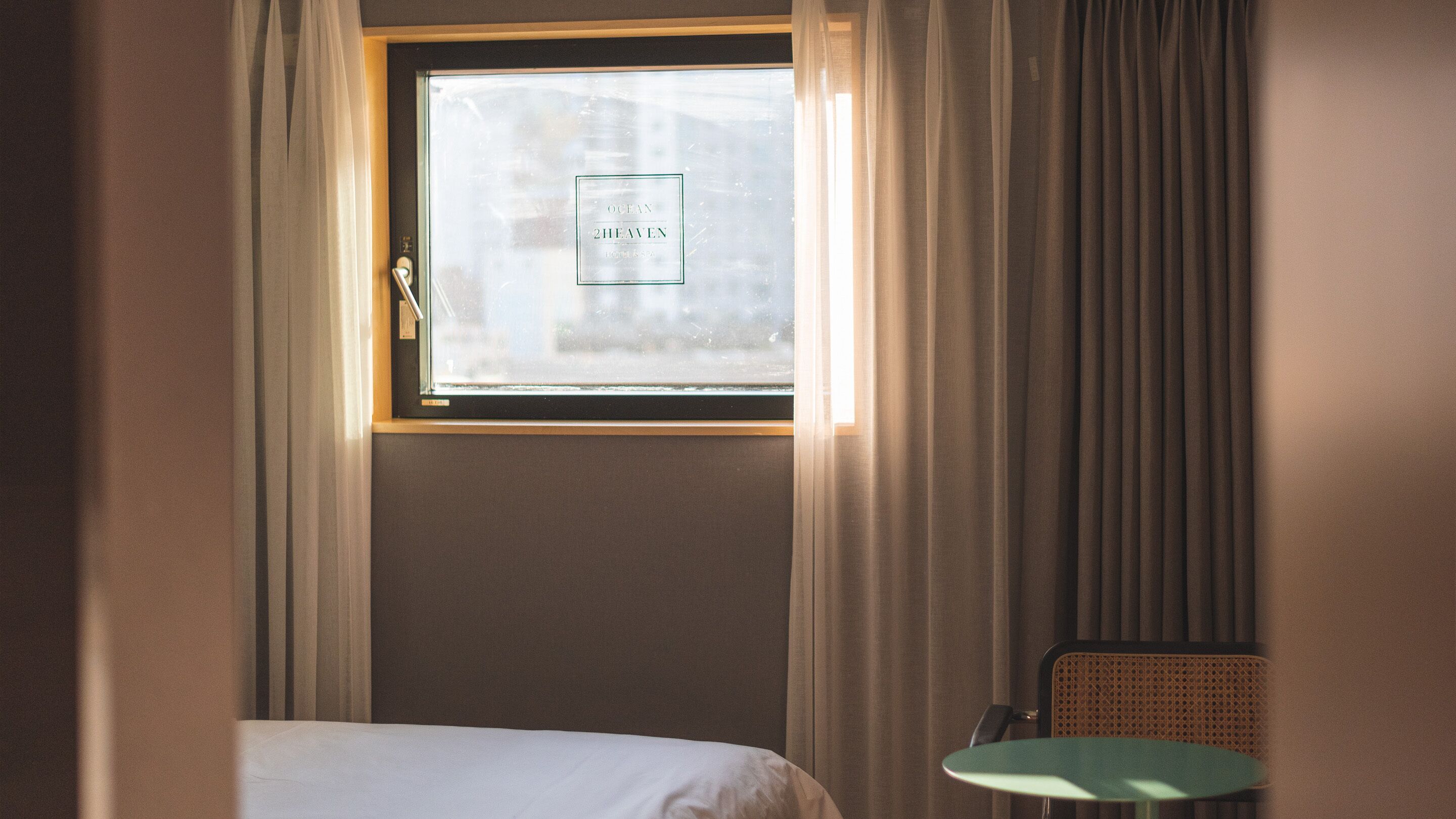 Camera d'albergo con un letto, un tavolino e una finestra che offre una vista sfocata sulla città.