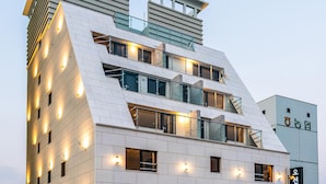 A multi-story building with a modern architectural design, featuring balconies and large windows. - Nampo Ocean 2 Heaven Hotel&Spa (Busan)