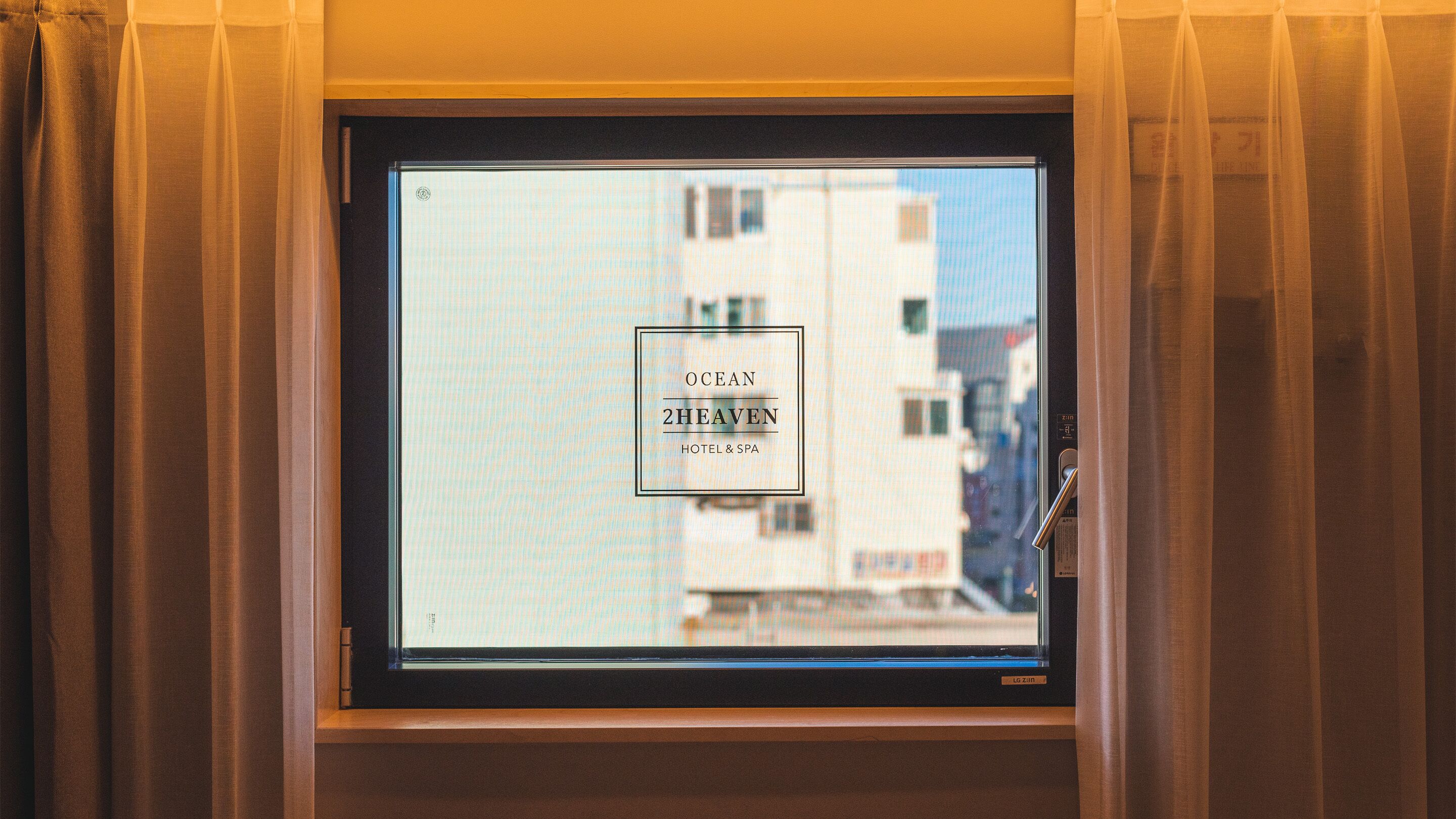 A window with a view of a building and the text "OCEAN 2HEAVEN HOTEL & SPA".