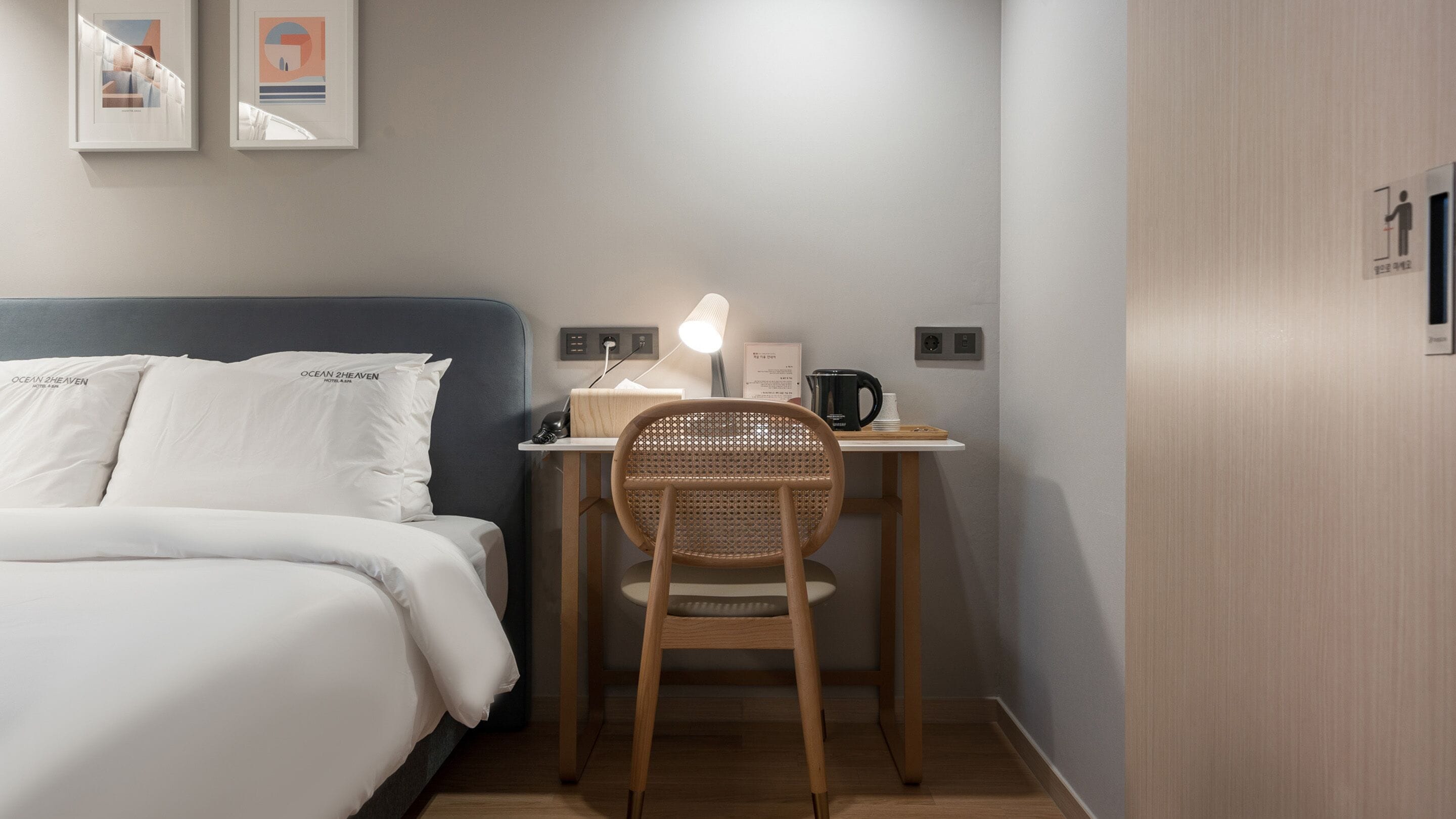 Una habitación de hotel con una cama, un escritorio con silla, una lámpara y una cafetera.