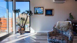 A modern living room with a large window, a patterned armchair, and two framed artworks on the wall. - Main Street Loft/Luxury 2nd Floor 1100 sq ft Condo (Cottonwood)