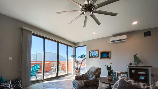 A spacious living room with a glass coffee table, a patterned armchair, a sofa, and a ceiling fan. - Main Street Loft/Luxury 2nd Floor 1100 sq ft Condo (Cottonwood)