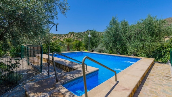 A rectangular swimming pool with a tiled deck and metal railings, surrounded by greenery and a clear sky. - Casa Mentesa La Guardia de Jaén by Ruralidays (Jaén)