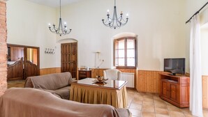 Ein gemütliches Wohnzimmer mit einer Couch, einem Esstisch, einem Fernseher und einem Holzschrank.