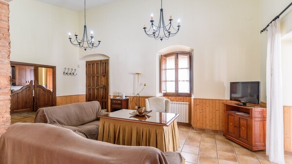 Una sala de estar con sofá, mesa de comedor, televisor y ventana.