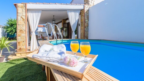 Ein Poolbereich mit Holztisch, Handtuch und zwei Gläser Orangensaft.