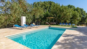 Relax by the pool surrounded by lush greenery and comfortable lounge chairs.