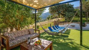 Un espacio al aire libre cubierto con una hamaca, un sofá y una mesa con bebidas y flores.