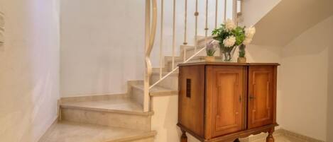 A staircase with a wooden cabinet at the bottom, a white railing, and a framed picture on the wall.