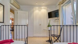A hotel room with two beds, a TV, a small table with a plant, and a window with curtains. - Villa Toscana by Interhome (Dénia)