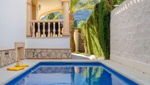 A swimming pool with a stone wall and a balcony. - Villa Toscana by Interhome (Dénia)