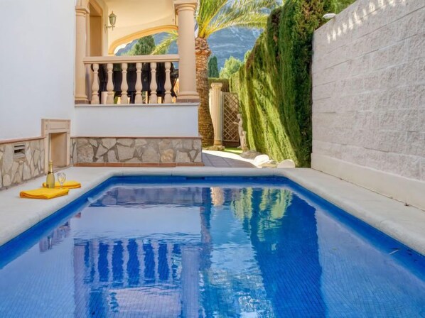 Una piscina con pared de piedra y balcón.