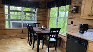 Eine Holzblockhütte mit Esstisch und Stühlen, einer Kaffeemaschine und einem Geschirrspüler.