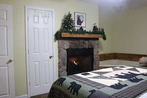 Una habitación con chimenea, un árbol de Navidad y una colcha con diseños de animales.