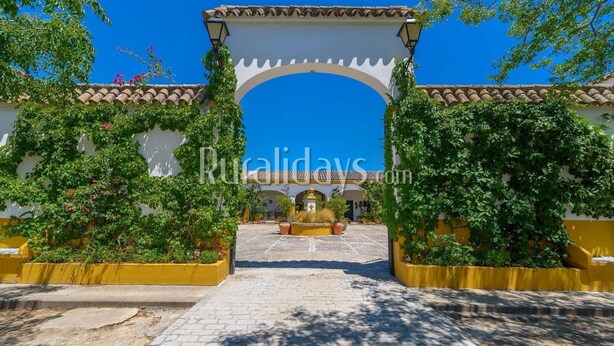 A courtyard with a white archway, potted plants, and a fountain.