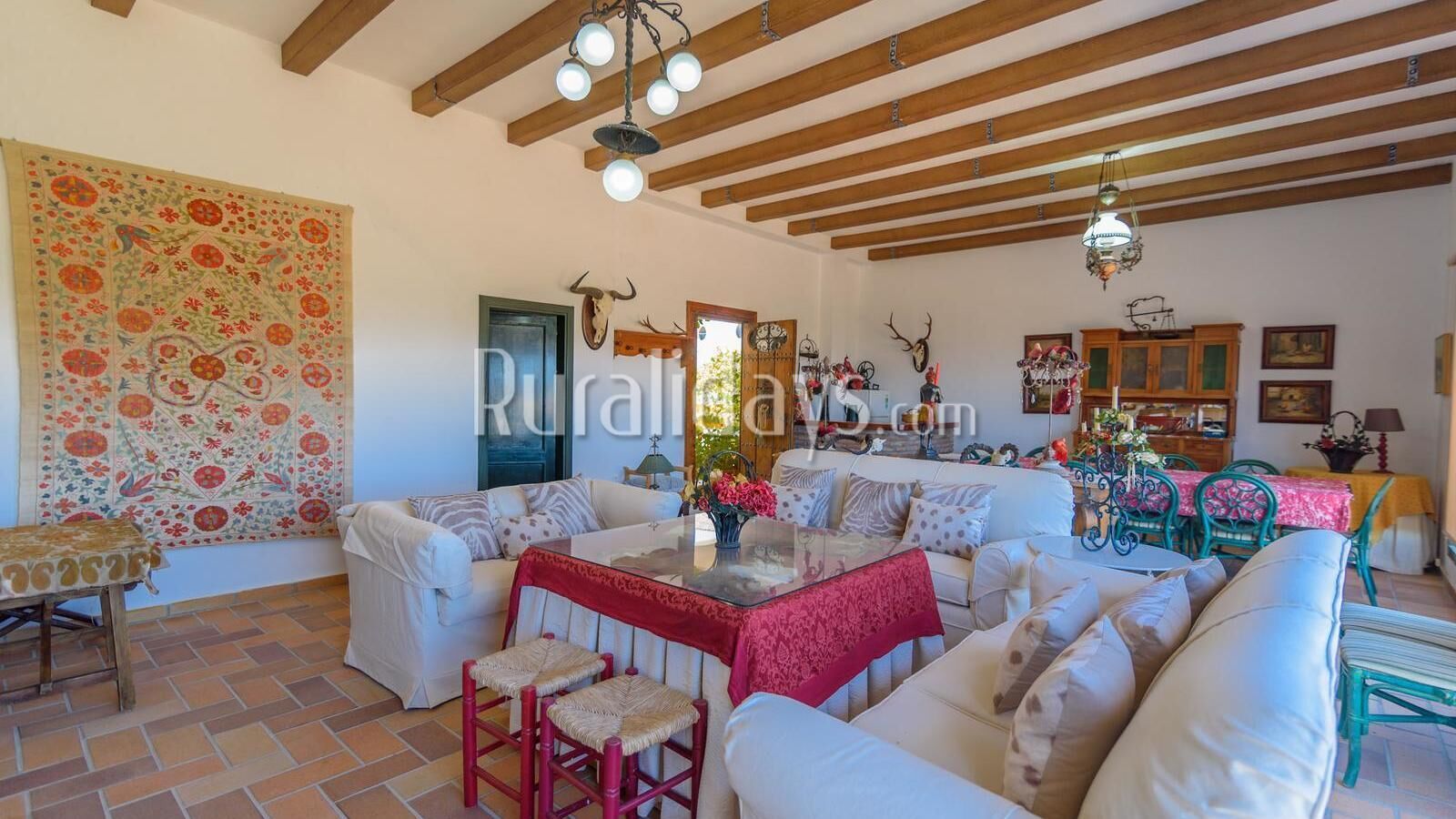 Un salon spacieux avec un haut plafond, une cheminée et un coin repas comprenant une table et des chaises.