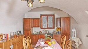 A cozy kitchen with wooden cabinets, a dining table set with a checkered tablecloth, and a variety of fruits. - Cosy apartment for 7 guests with A/C, pool, WIFI, TV, patio and pets allowed (Salò)