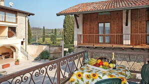 A balcony with a table set for dining, featuring a variety of fruits and a bottle of wine. - Cosy apartment for 7 guests with A/C, pool, WIFI, TV, patio and pets allowed (Salò)