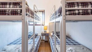 Une chambre de dortoir avec des lits superposés, un bureau et une lampe.