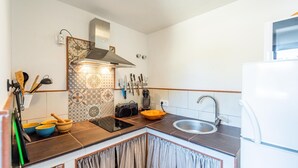 Une cuisine équipée d’une cuisinière, d’un évier et de divers ustensiles.