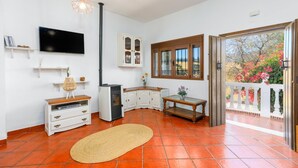 A kitchen with white cabinets, a black stove, and a wooden table. - Casa El Mirador Montecorto by Ruralidays (Málaga)