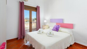 A hotel room with a bed, a nightstand, a lamp, a window with curtains, and a view of the outdoors. - Casa El Mirador Montecorto by Ruralidays (Málaga)