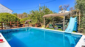 A swimming pool with a slide, surrounded by greenery and a wooden fence. - Casa Rural La Milla Verde Málaga - Campanillas by Ruralidays (Málaga)