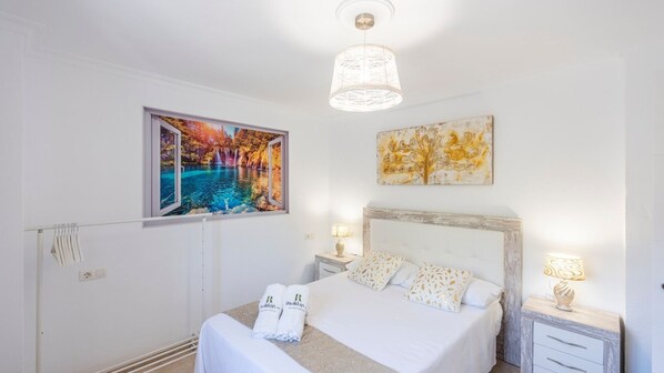 A bedroom with a large bed, two bedside tables, a hanging light fixture, and artwork on the walls. - Villa Felicidad Sayalonga by Ruralidays (Málaga)