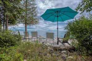 A beachside seating area with a large umbrella, chairs, and a view of the water. - Waterfront, Dog Friendly Sherwood Point (Sturgeon Bay)