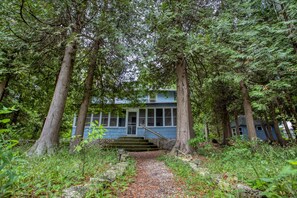 A house surrounded by tall trees with a gravel path leading to the front door. - Waterfront, Dog Friendly Sherwood Point (Sturgeon Bay)