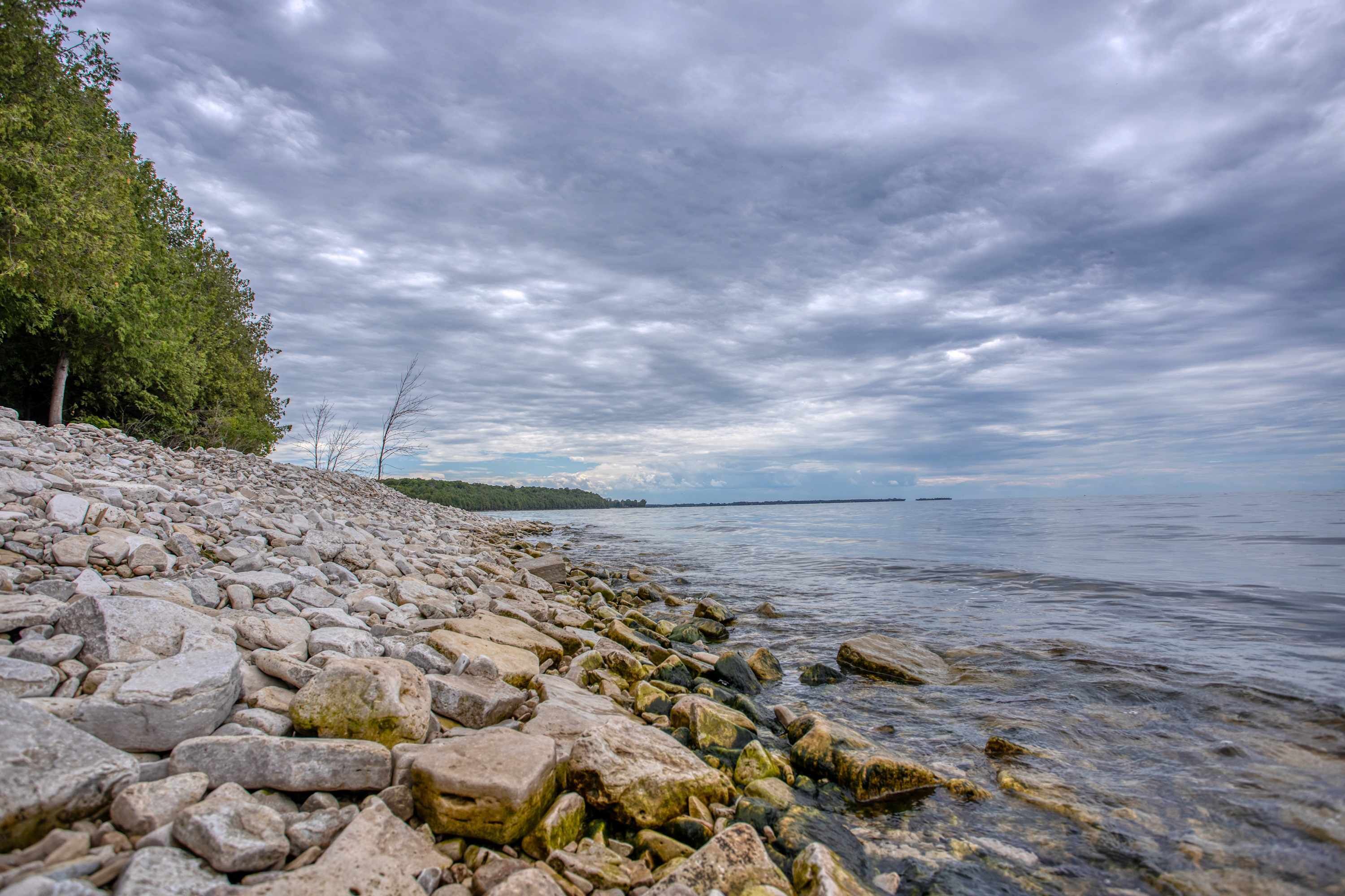 Un rivage rocheux, avec une eau claire et un ciel nuageux.