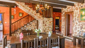 Un espace repas avec une table et des chaises en bois, un escalier avec des murs en pierre et un lustre.