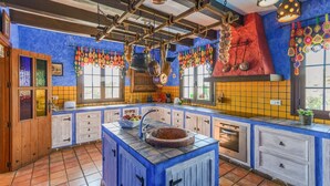 Une cuisine avec des meubles bleus, un îlot central doté d’un évier et un pare-feu rouge.