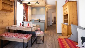 A cozy room with wooden walls and furniture, a dining area with a table and benches, and a kitchenette in the background. - Le Prariond (Val Claret) by Interhome (Tignes)