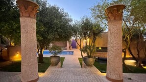A pathway leading to a pool area with decorative columns and potted plants. - Marrakesh 6-Bed Housing Authentic Berber (Marrakesh)
