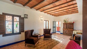 A spacious living room with two brown armchairs, a wooden cabinet, and a tiled floor. - Cortijo Carrillo Antequera by Ruralidays (Málaga)