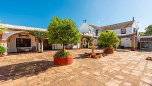 A courtyard with potted trees, a fountain, and traditional architecture. - Cortijo Carrillo Antequera by Ruralidays (Málaga)