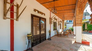 A covered patio area with a wooden ceiling, a red vertical stripe on the wall, and a door with glass panels. - Cortijo Carrillo Antequera by Ruralidays (Málaga)