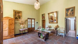 A room with a wooden cabinet, a table with floral arrangements, and a mirror on the wall. - Cortijo Carrillo Antequera by Ruralidays (Málaga)