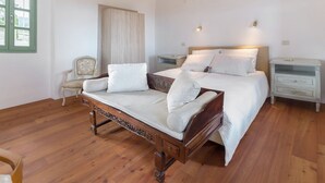 A bedroom with a wooden bed, a nightstand, a chair, and a window with green shutters.