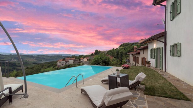 A swimming pool with lounge chairs and a stone patio.