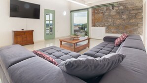 A modern living room with a grey sectional sofa, a wooden coffee table, and a flat-screen TV mounted on the wall.
