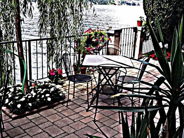 A patio with a table and chairs, potted plants, and a view of the water.