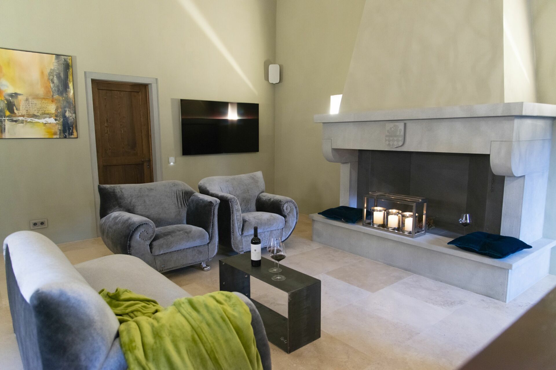 Un salon avec deux fauteuils gris, une table basse, une cheminée et un téléviseur à écran plat fixé au mur.