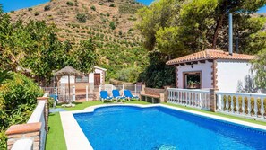 A swimming pool with a white deck, surrounded by a white fence and a small building with a tiled roof. - Villa Virginia Arenas by Ruralidays (Málaga)